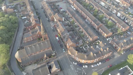 antena de drones perspectiva de ojo de pájaro sobre casas de ciudad británicas - iglesia con campanario al amanecer órbita izquierda