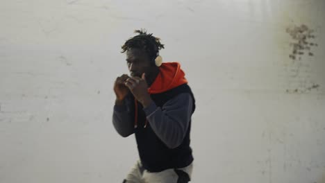 afro american young male boxer practicing shadowboxing in headphones