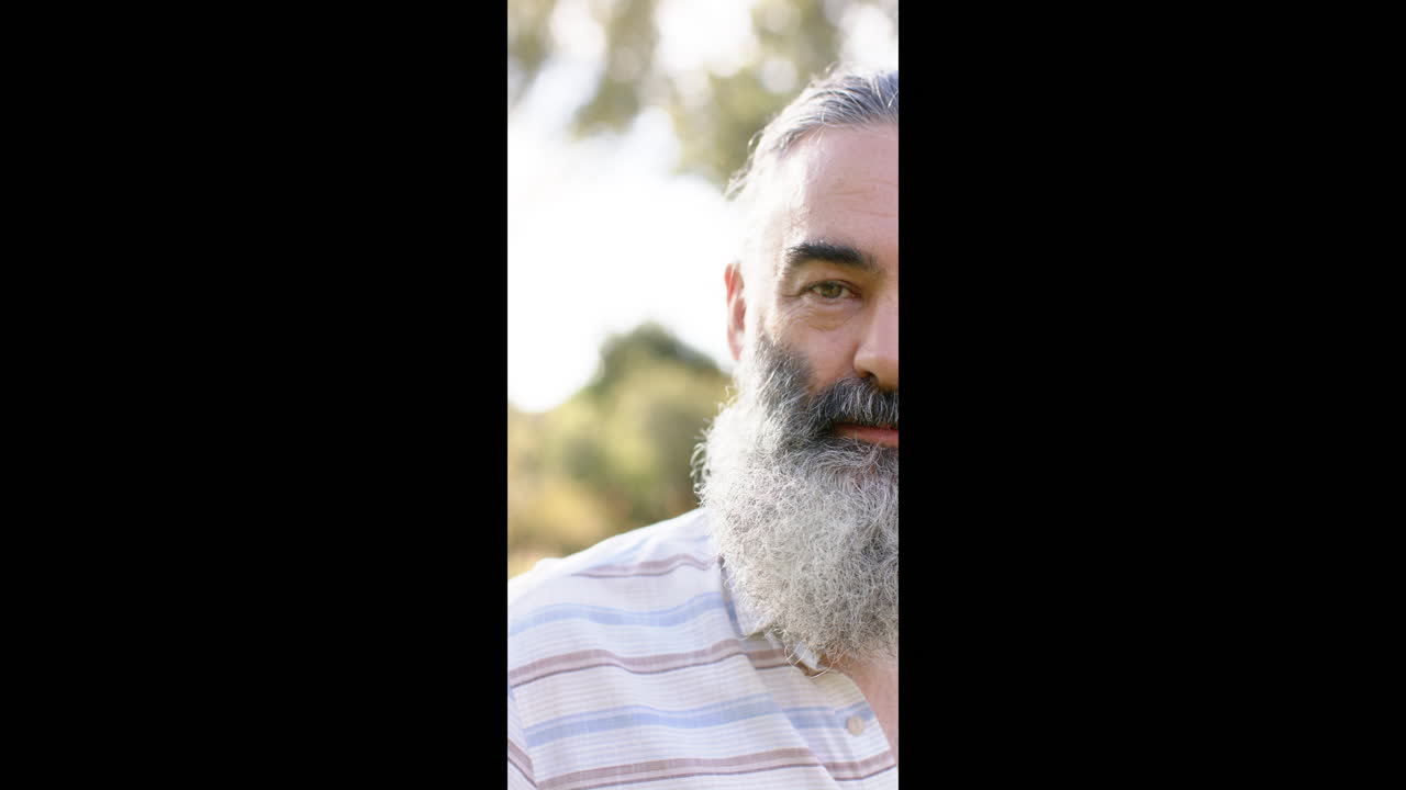 Vertical video: Smiling senior man with beard enjoying outdoor time in nature