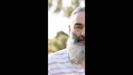 vertical video: smiling senior man with beard enjoying outdoor time in nature