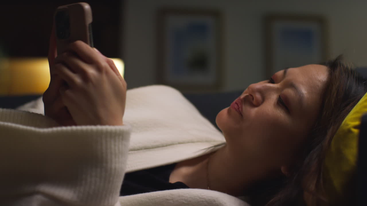 집에서 저녁을 보내고 소파에 누워서 인터넷이나 소셜 미디어를 스크롤하는 여성의 클로즈업 8