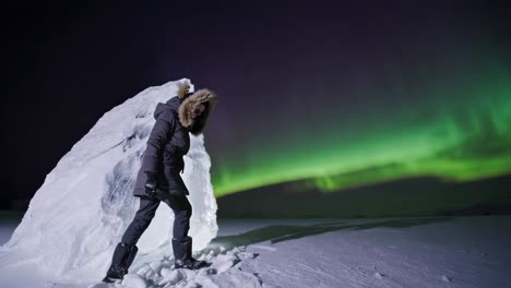 persona caminando por un iceberg con la aurora boreal