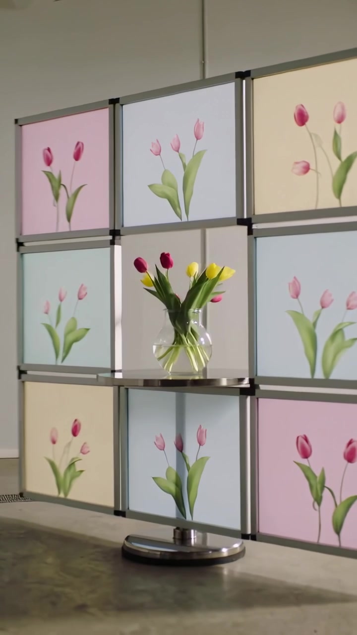 Vídeo vertical: Unidade de exibição modular giratória em base motorizada mostrando vaso de tulipas em showroom.