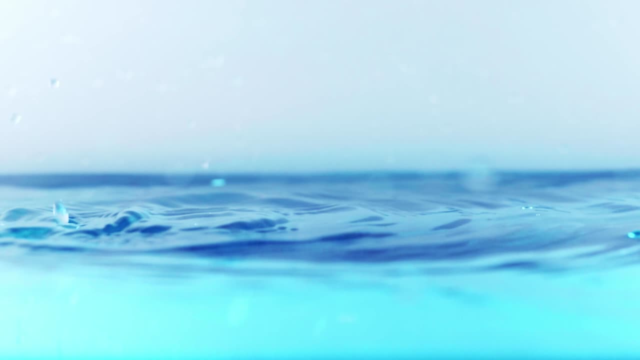 슬로우 모션의 깨끗한 물 표면은 물이 튀는 상점으로 화면을 채우고 기포로 액체 표면을 흔들고 있습니다.