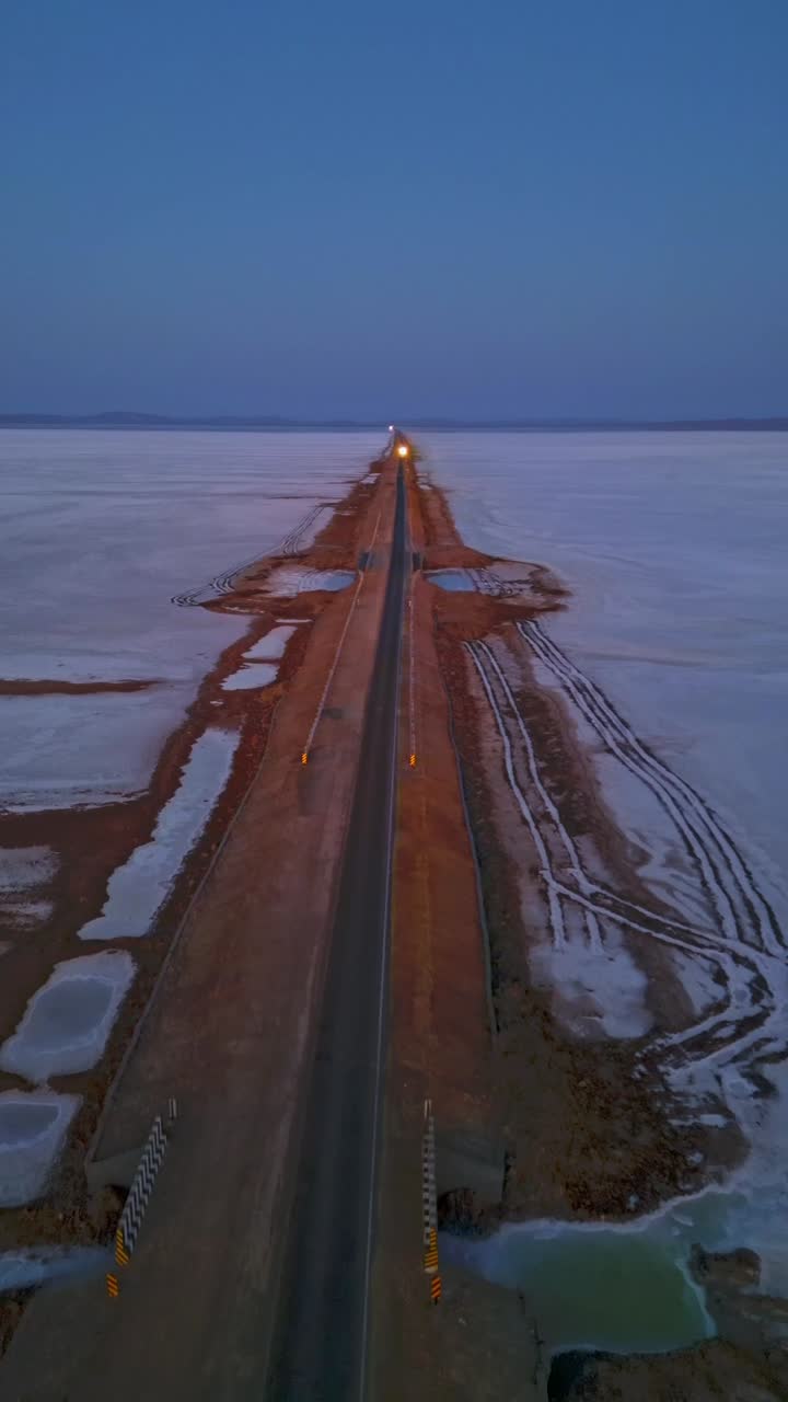 A forward moving aerial view of the Rann of Kutch, Gujarat, India reveals an endless white salt desert stretching to the horizon, glowing softly under clear evening sky 4K