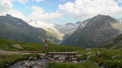 a blonde girl in a short, white dress walks across a river from right to left