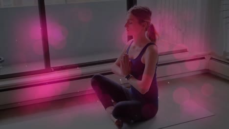 animation of pink glowing spots over caucasian fit woman practicing yoga at home