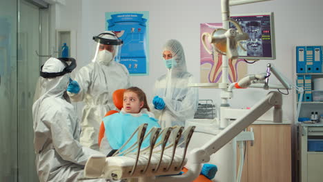 pediatric dentist wearing protection suit treating girl patient