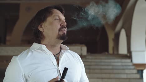 retrato de un joven brutal con barba que mira a la distancia y fuma una pipa de cerca