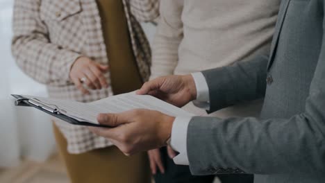 Real-estate-agent-landlord-explaining-the-rental-agreement-to-the-renters,-caucasian-faceless-people