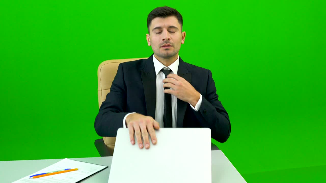 초록색 배경의 책상에서 일하는 가방을 가진 남자