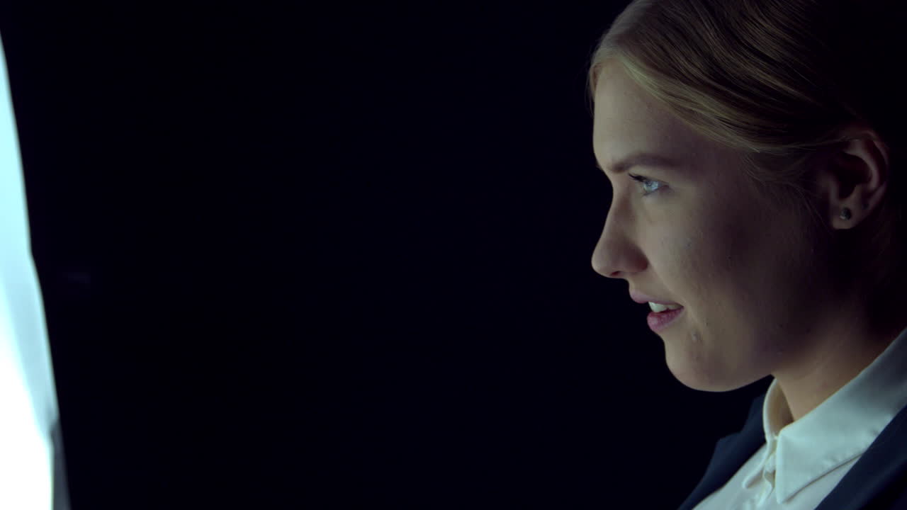 Woman pointing copy space on virtual screen. Blond businesswoman against black background,