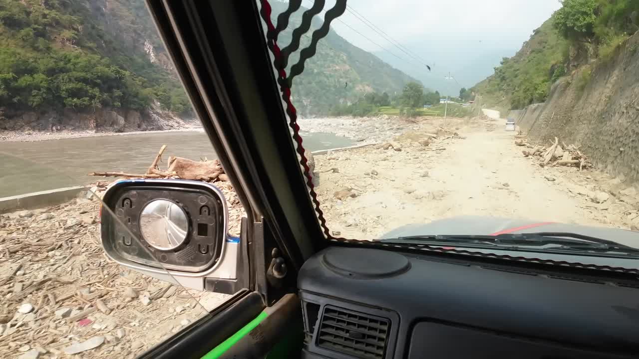 POV jeep ride through Nepal's rugged interior. Slowly driving on a destroyed dirt road in the valley next to Sunkoshi river