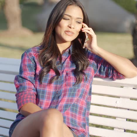 mujer que usa el teléfono celular en un banco del parque