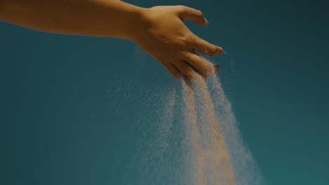 sand slipping slowly through a person's fingers