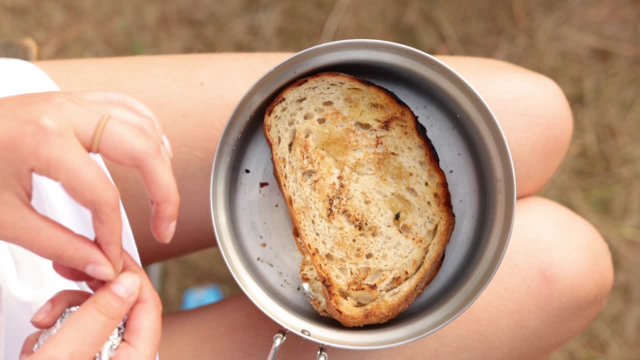Donna che toglie il panino dalla pellicola o dal contenitore, vacanza all'aperto, primo piano.