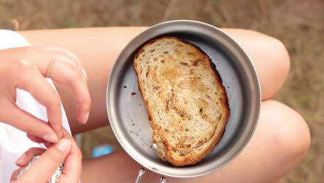 female cleans sandwich from foil i container, outdoor vacation, close up