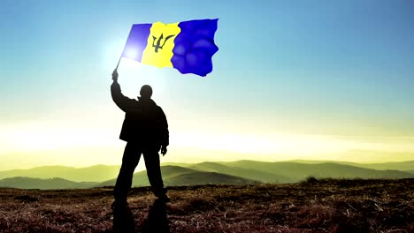 successful silhouette man winner waving barbados flag on top of the mountain peak. cinemagraph loop background