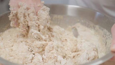 closeup on hands kneading yeast dough in the metal bowl