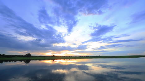 sunset with cloudy grey and blue skies along the upper reaches of the chobe river in summer