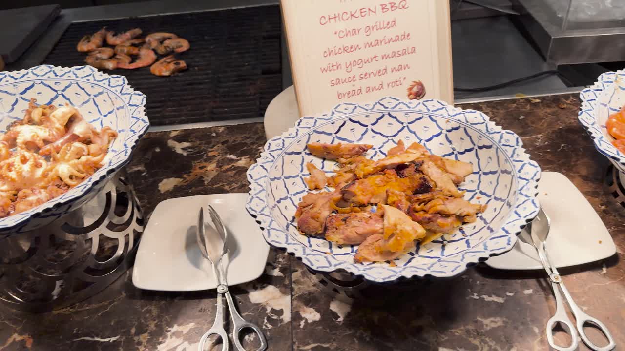 푸켓 리조트의 뷔페에서 다양한 요리가 전시되어 있습니다. 따뜻한 조명은 우아한 프레젠테이션과 다양한 요리를 강조합니다.