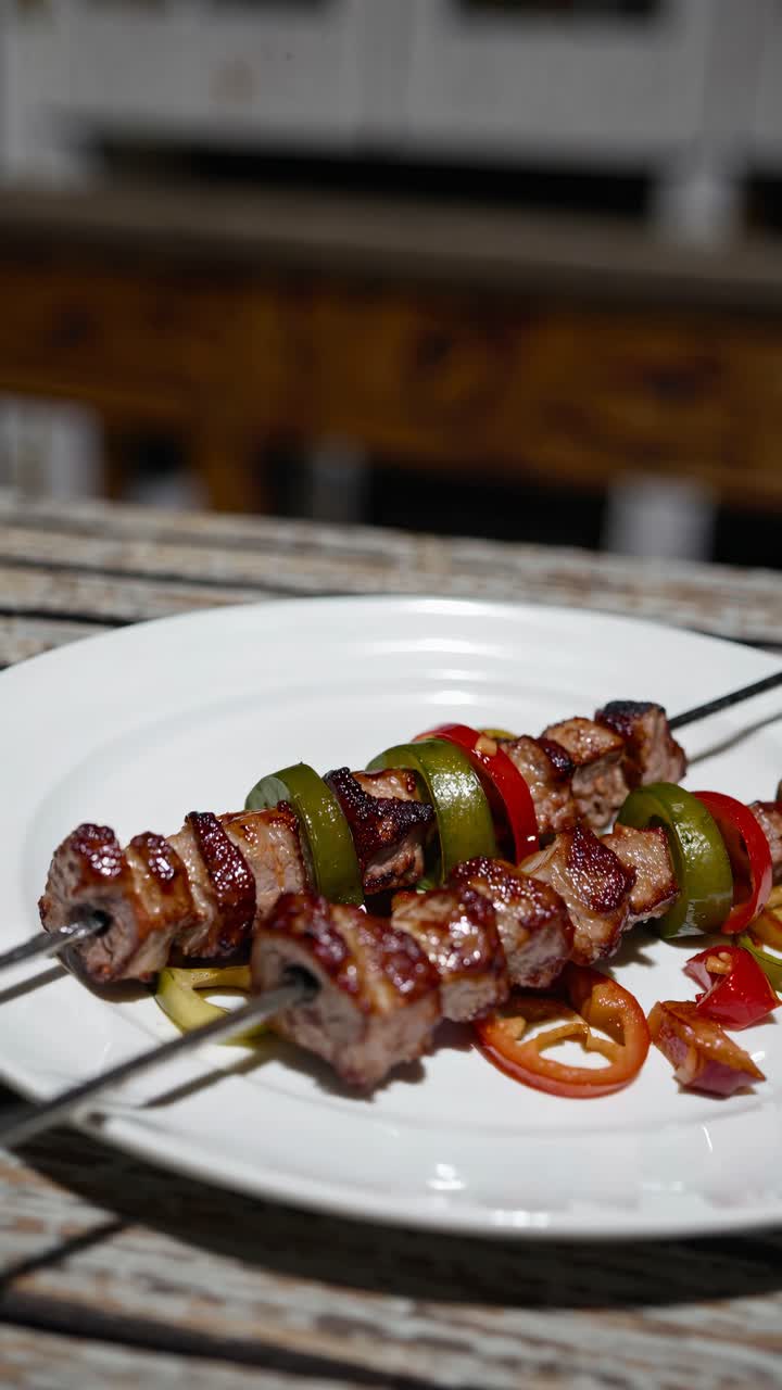 Angolo di ripresa ravvicinato di spiedini grigliati con carne e verdure su un piatto bianco