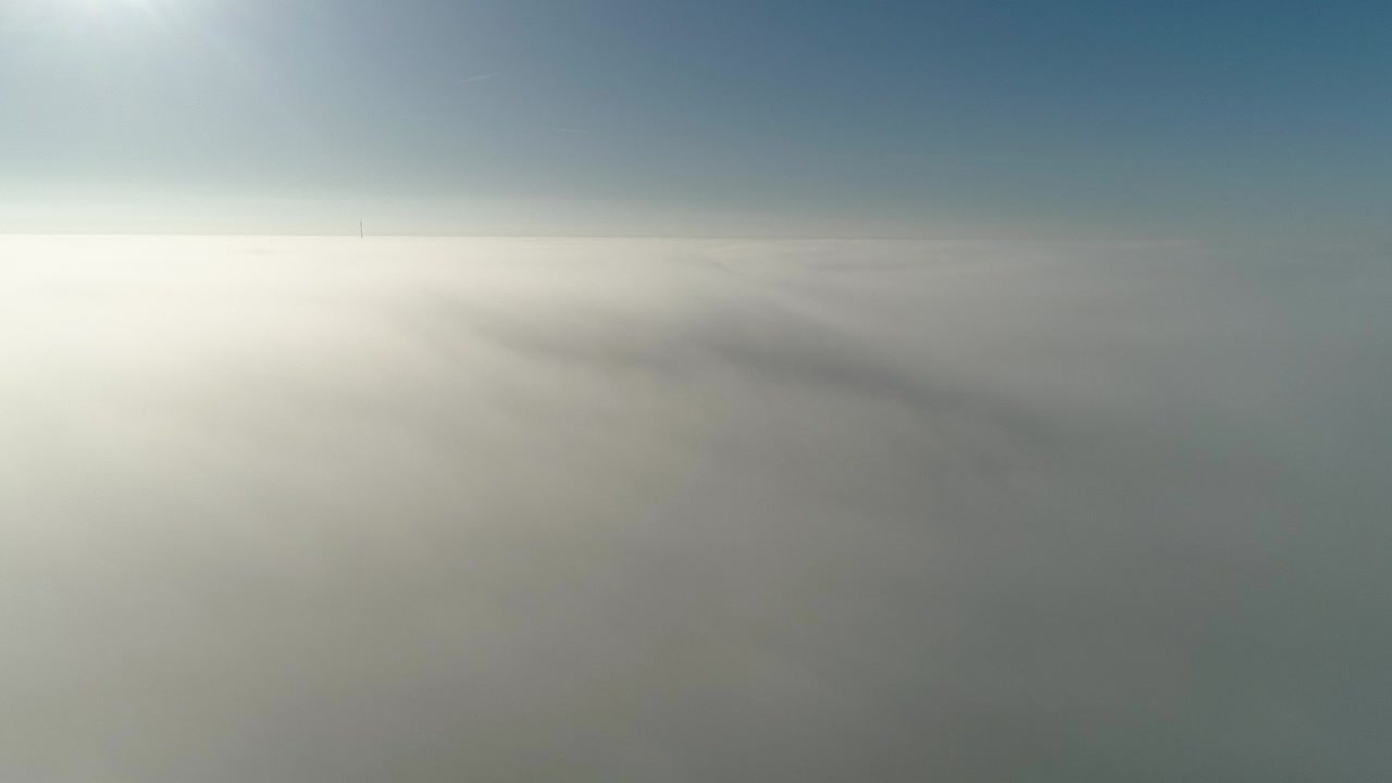 vuelo sobre nubes brumosas a la luz del sol de la mañana con poca gloria y paisaje urbano bajo las nubes