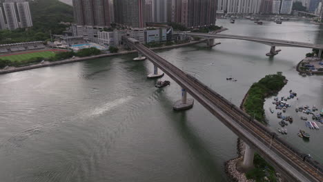 MTR-train-driving-over-a-bridge-while-a-barge-is-sailing-on-the-water