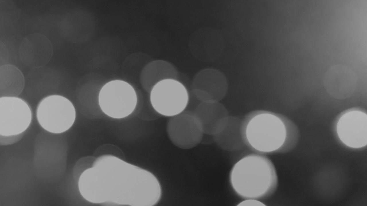 Abstract out of focus traffic lights creating glowing bokeh orbs on misty night road