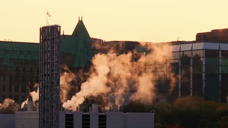 vapor saliendo de un edificio industrial en el centro de ottawa en una mañana soleada con edificios gubernamentales y una bandera de canadá en el fondo