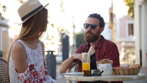 young couple talking over drinks outside a cafe