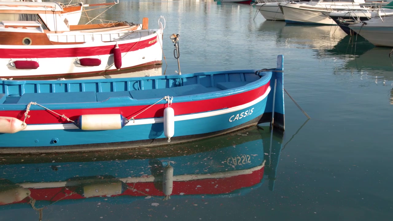 Inquadratura media statica di una barca di legno colorata ormeggiata nelle calme acque di un porto mediterraneo