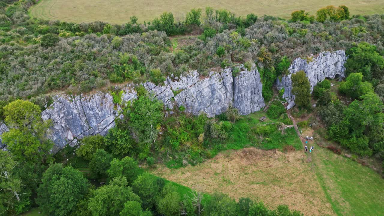 Aerial View of a Cliff Face with a Cave and People Hiking