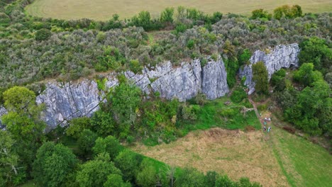 aerial view of a cliff face with a cave and people hiking