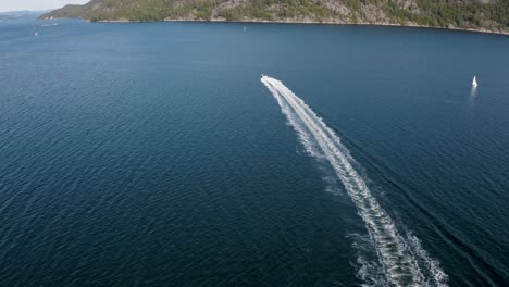 boat speeds away straight into the distance while the drone ascends up in 4k