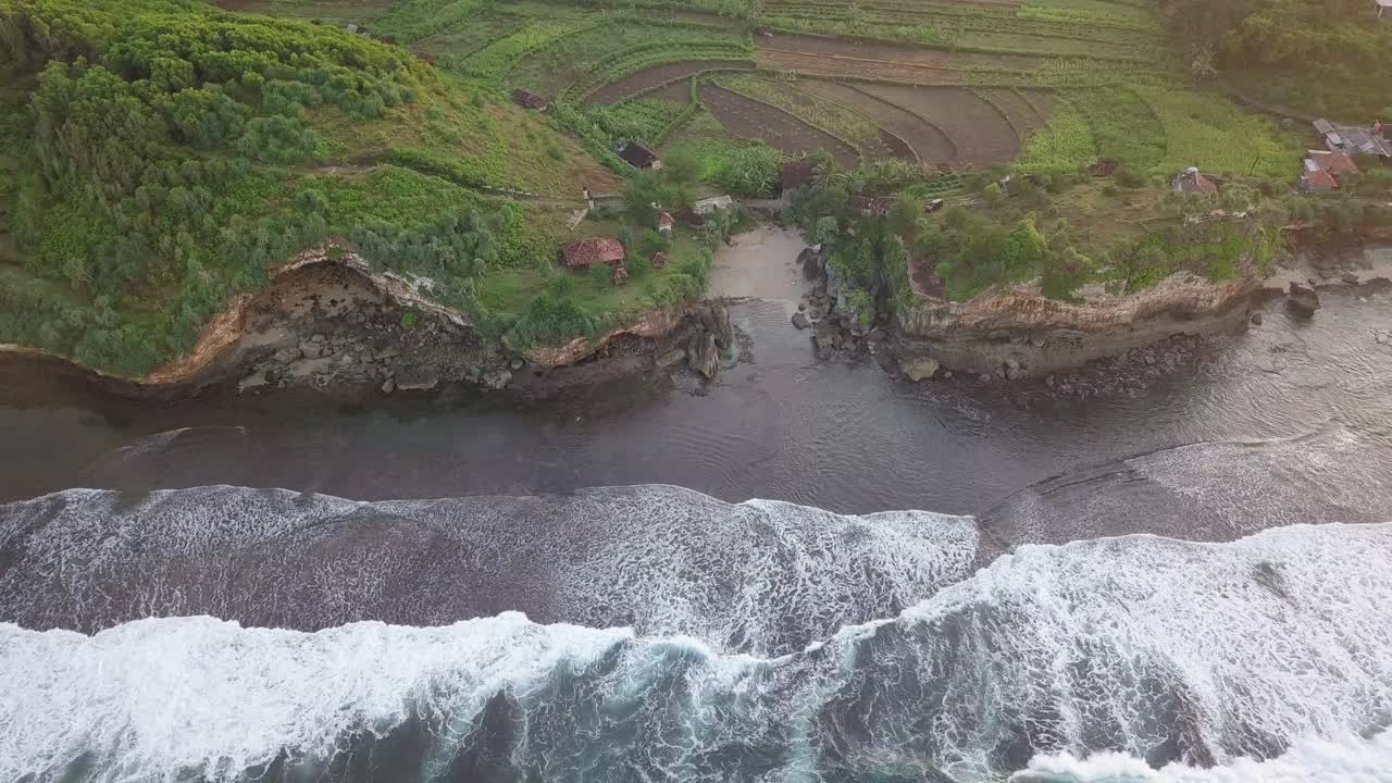 aerial view of a small private sandy beach between the cliffs of an island in indonesia