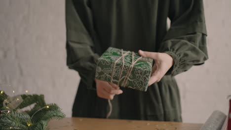 close-up girl wraps up a gift and ties it with a rope