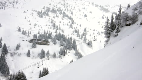 Time-lapse-of-a-ski-chair-lift-in-the-resort-of-Praz-sur-Arly,-with-trees-and-mountain-background