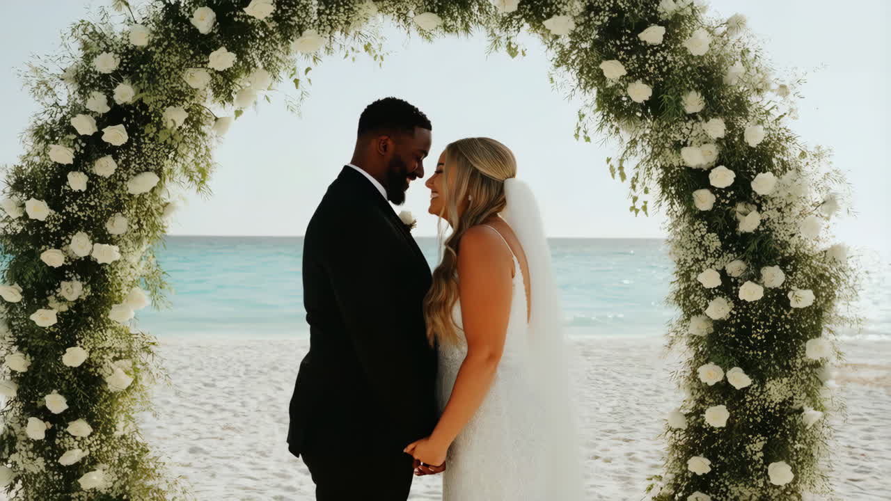 A happy couple exchanges vows under a floral arch on a pristine beach
