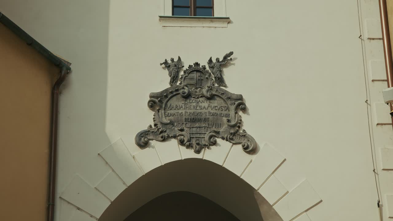 Intricate stone plaque with Latin inscription above an archway on Michael's Gate in Bratislava