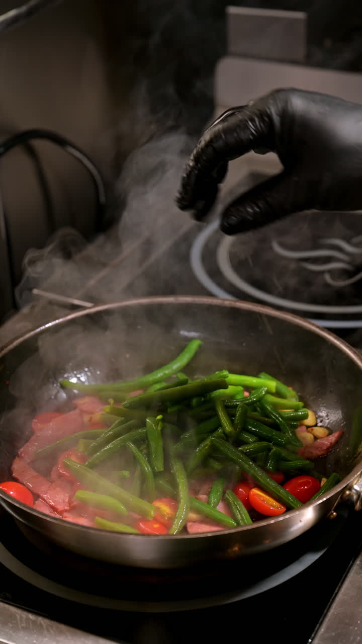 Bratpfanne mit Schinken, grünen Bohnen und Tomaten. Schinken, grüne Bohnen, Tomaten und Knoblauch werden beim Kochen zusammen in einer Pfanne gebraten
