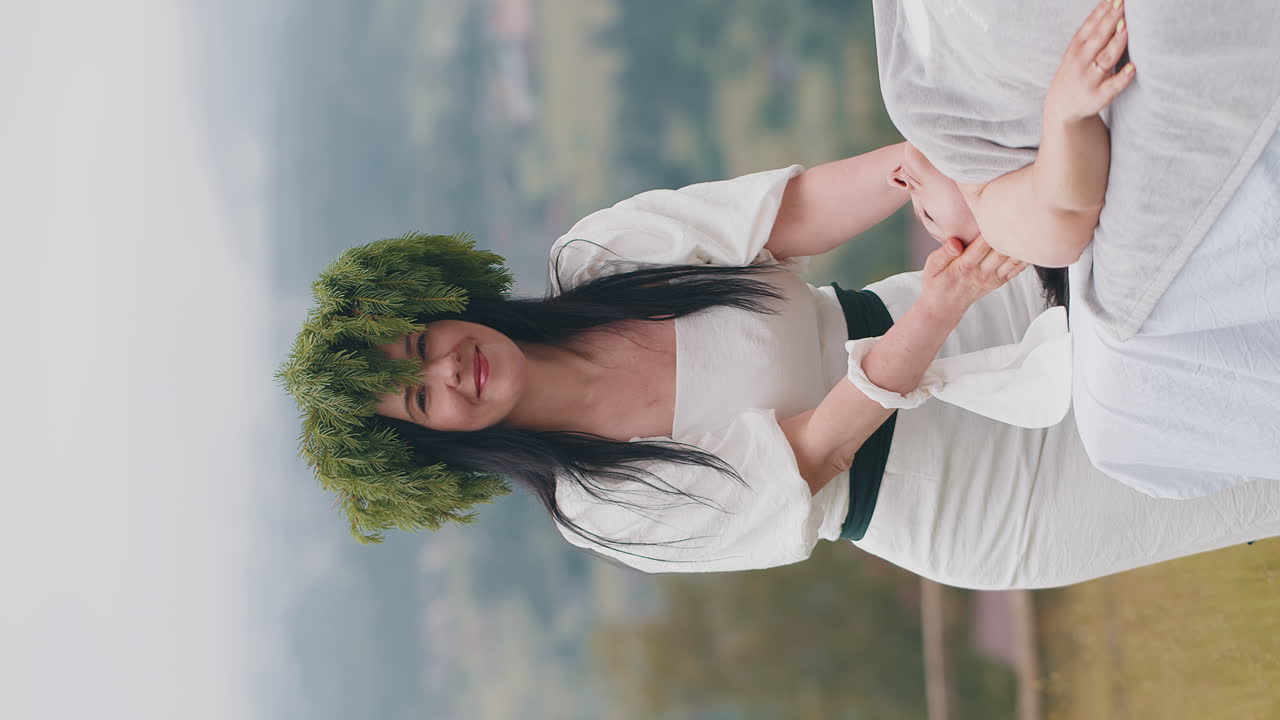 테라피스트 여성 의사는 여성이 휴식을 취하는 스파 얼굴 마사지를 산의 야외에서 손으로 만니다.