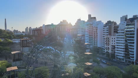 drone flyover punto de referencia icónico del parque sarmiento, una vieja rueda de ferris de hierro de gustave eiffel, revela la escalera y los edificios residenciales al atardecer con una hermosa llamarada solar