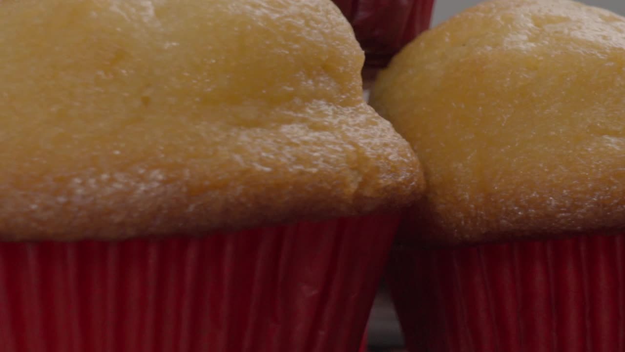 Close-up of stacked golden muffins in red liners with a soft texture and a blurred background