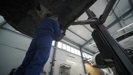 auto mechanic working underneath car lifting machine at the garage. auto repair shop. car service, repair.