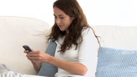 mujer positiva enviando un mensaje de texto en el sofá