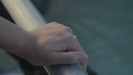 해변에서 레일링을 들고 있는 손의 클로즈업  ⁇