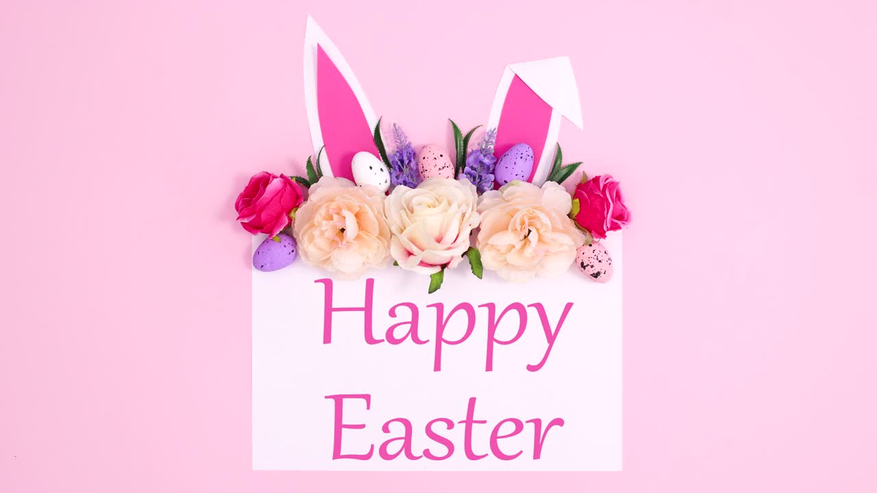 Testo "Buona Pasqua" scritto su carta con composizione floreale e orecchie da coniglio. Stop motion