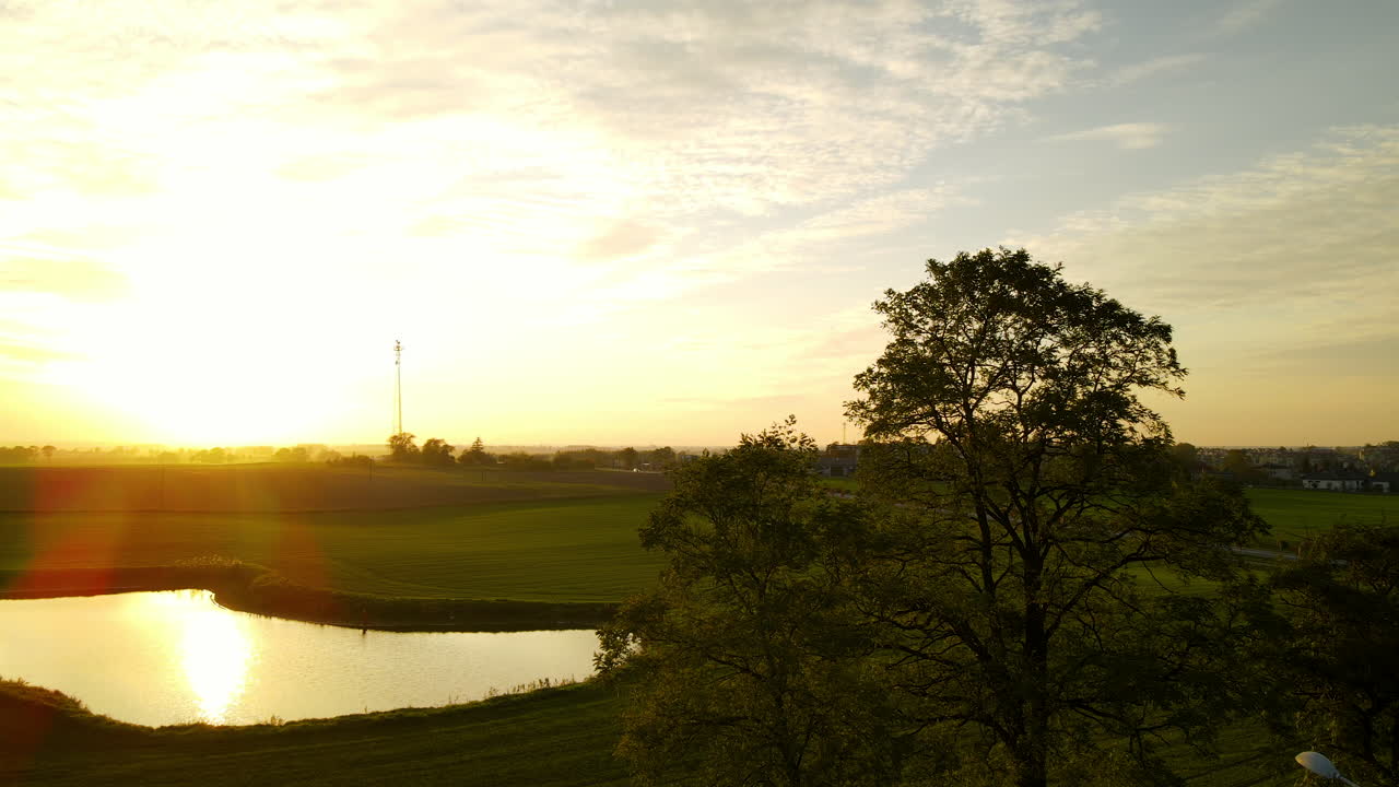 햇빛은 폴란드 루바바 마을 근처의 초원 풍경에 있는 잔잔한 호수에서 반사되고 조명됩니다.