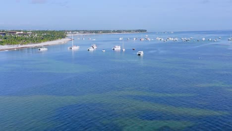 vista aérea hacia adelante sobre las aguas turquesas de la playa bavaro y los barcos amarrados en punta cana